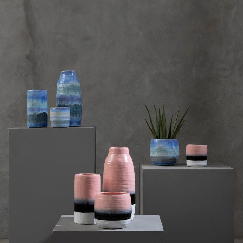 Vases with gradient colors on gray pedestals against a dark gray background