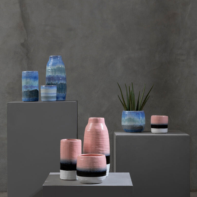 Vases with gradient colors on gray pedestals against a dark gray background
