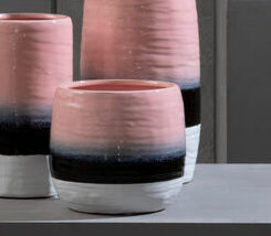 Vases with gradient colors on gray pedestals against a dark gray background
