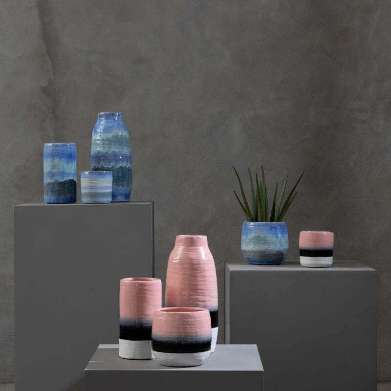 Vases with gradient colors on gray pedestals against a dark gray background