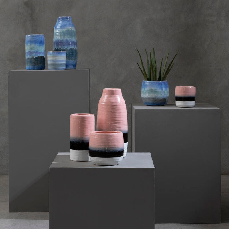Vases with gradient colors on gray pedestals against a dark gray background