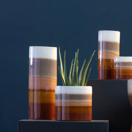 Collection of ceramic planters with striped patterns on a dark background