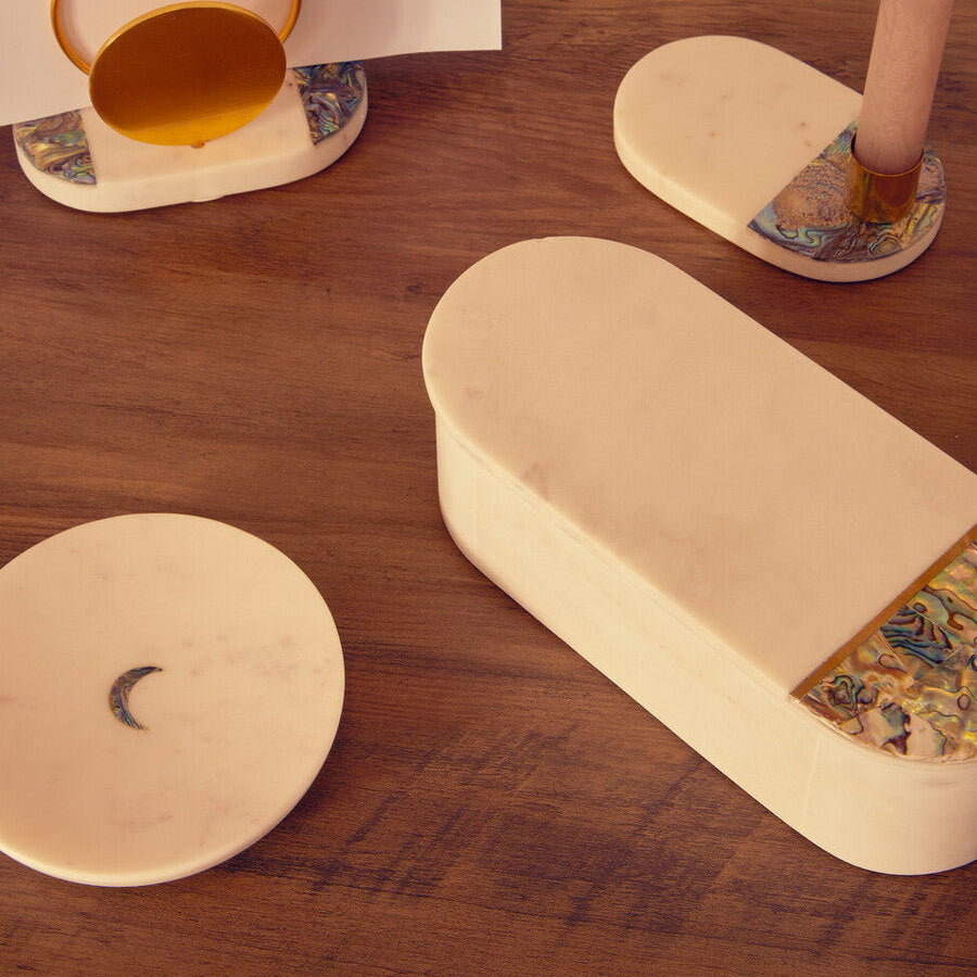 Decorative items on a wooden surface including a cylindrical box, a round coaster, and a small cup.