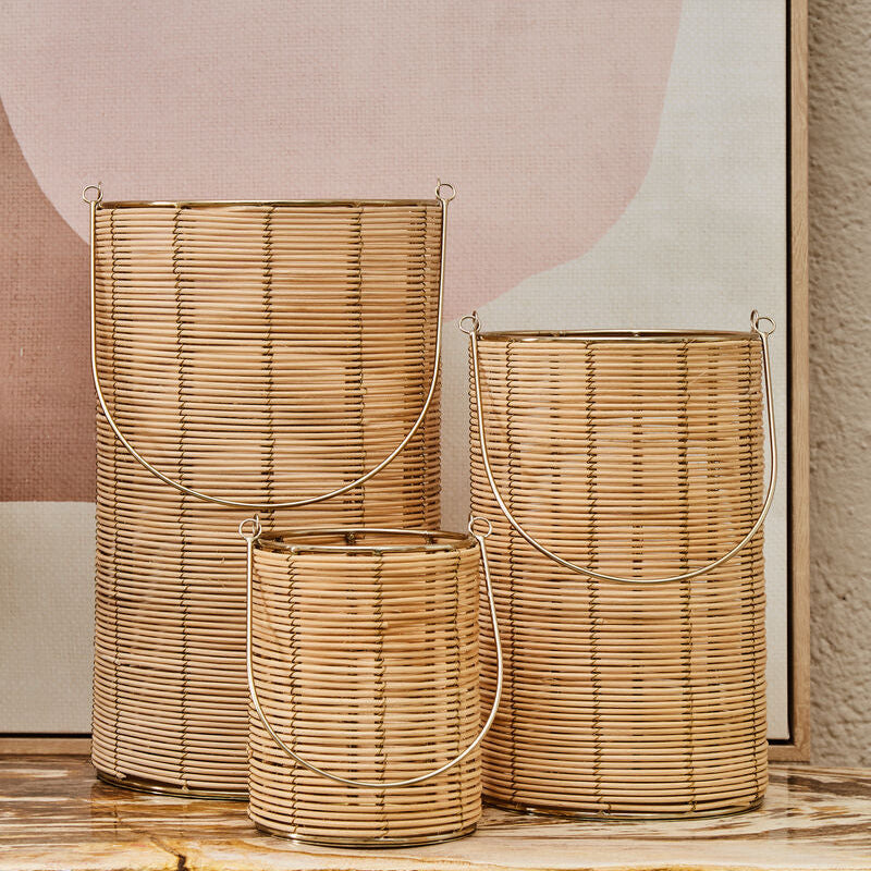 Three woven baskets of different sizes on a wooden surface with a abstract wall art in the background.