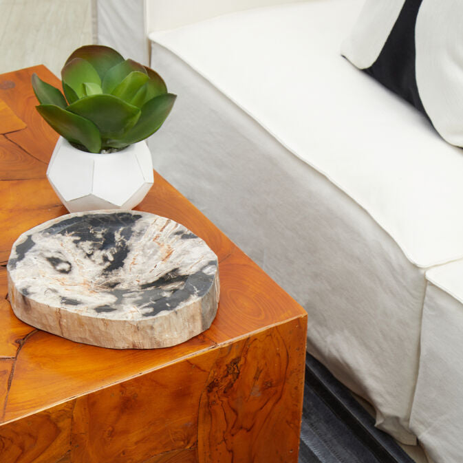 Wooden coffee table with a plant and decorative item next to a white sofa.