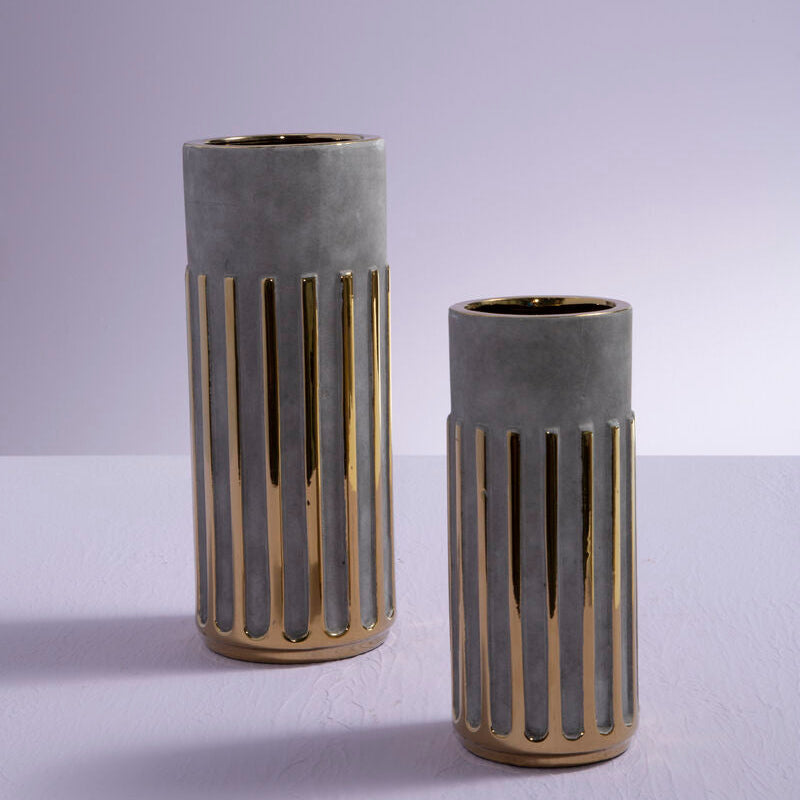 Two concrete vases with gold accents on a light gray background