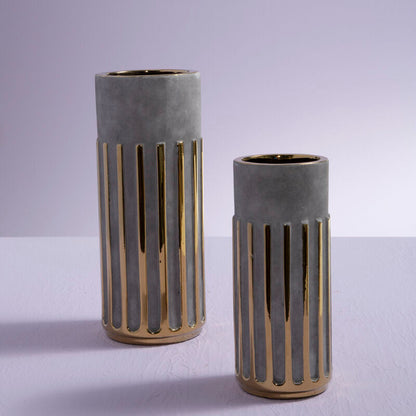 Two concrete vases with gold accents on a light gray background