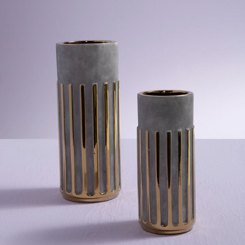 Two concrete vases with gold accents on a light gray background
