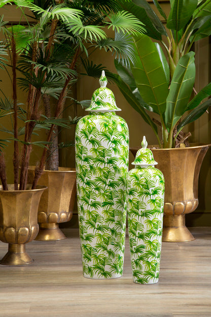 Two green and white patterned vases on a wooden surface with plants in the background.