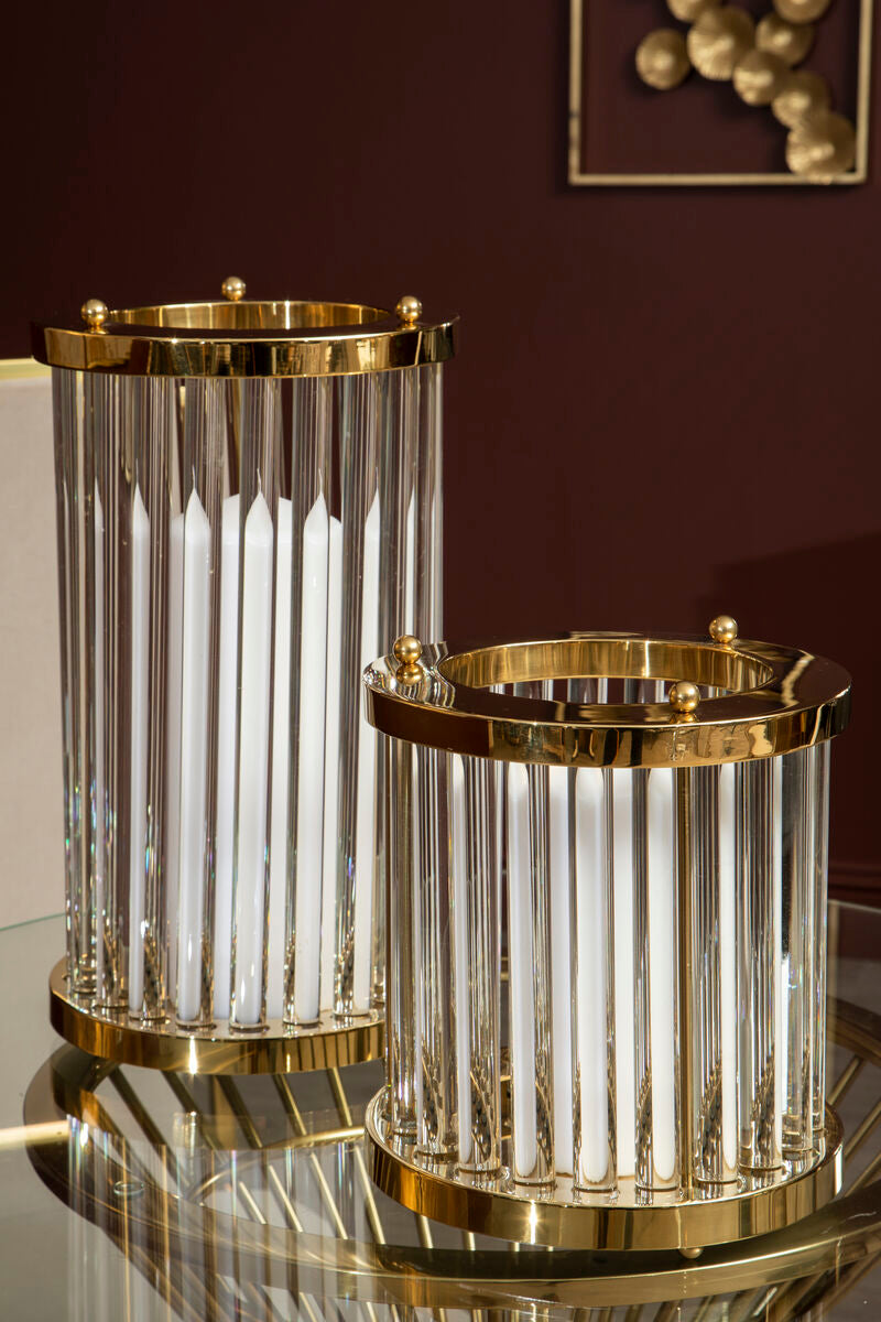Two cylindrical glass containers with gold accents on a reflective surface.