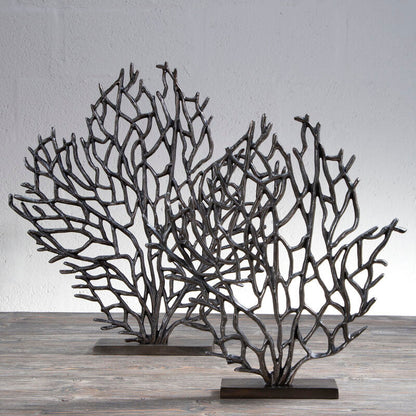 Decorative metal coral sculptures on a wooden surface with a gray background