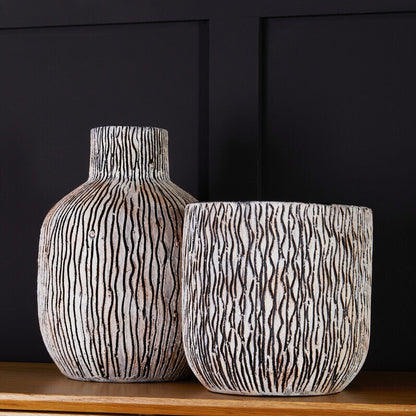 Two textured vases on a wooden surface with a black background