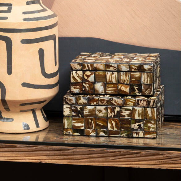 Ceramic vase with geometric patterns on a shelf against a abstract wall.