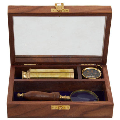 Wooden box with brass telescope, magnifying glass, and compass on a white background