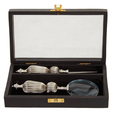 Set of silver spoons and a magnifying glass in an open black display case.