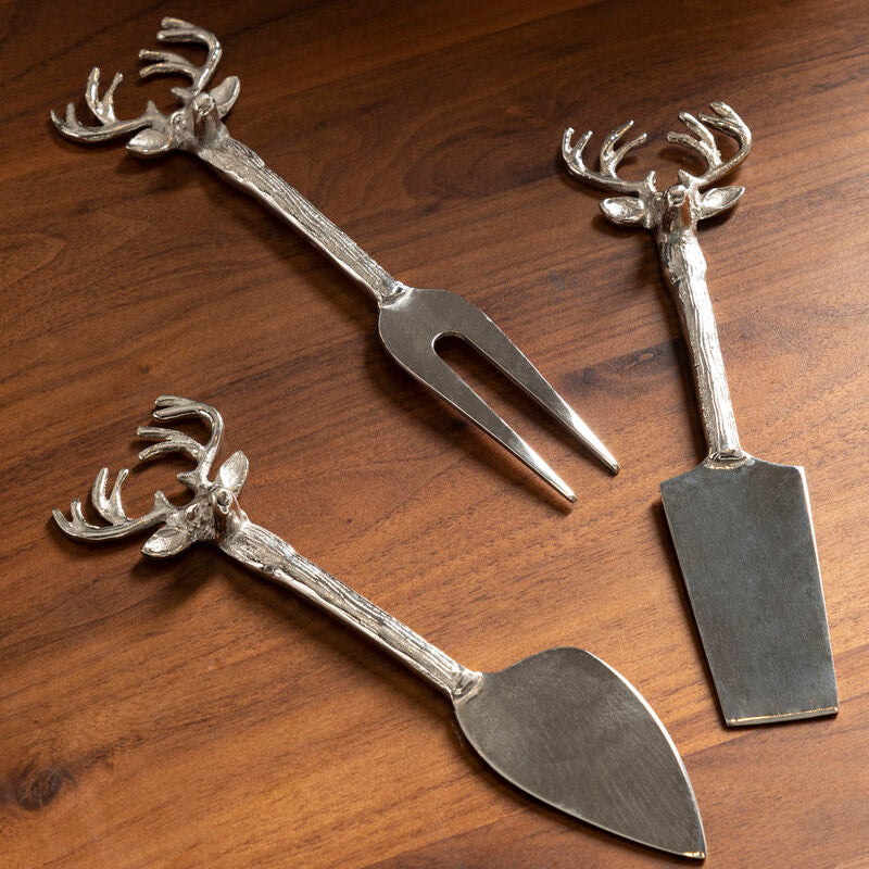 Three metal utensils with deer head designs on a wooden surface