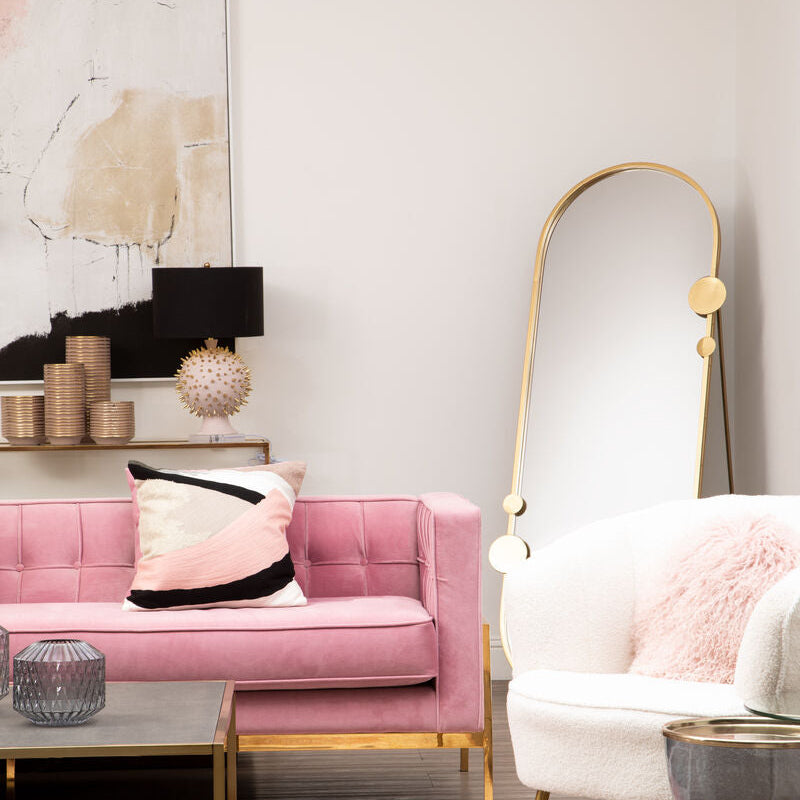 Modern living room with pink sofa, white armchair, and gold accents.