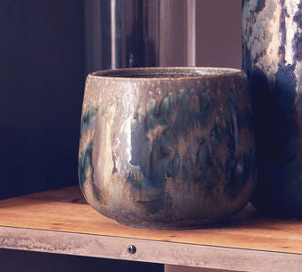 Wooden shelf with decorative vases and glasses against a plain wall