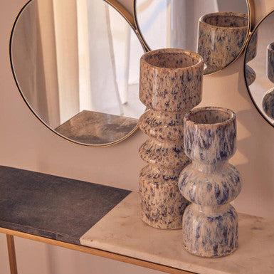 Decorative candle holders on a shelf with a mirror in the background