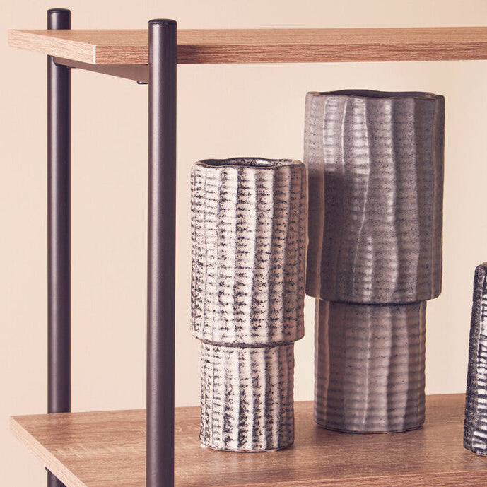 Wooden shelf with metal legs holding three textured vases against a beige background