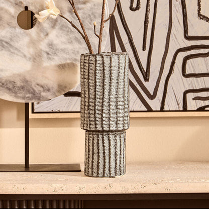 Decorative setup with a marble-patterned lamp, vase with branches, and abstract wall art.