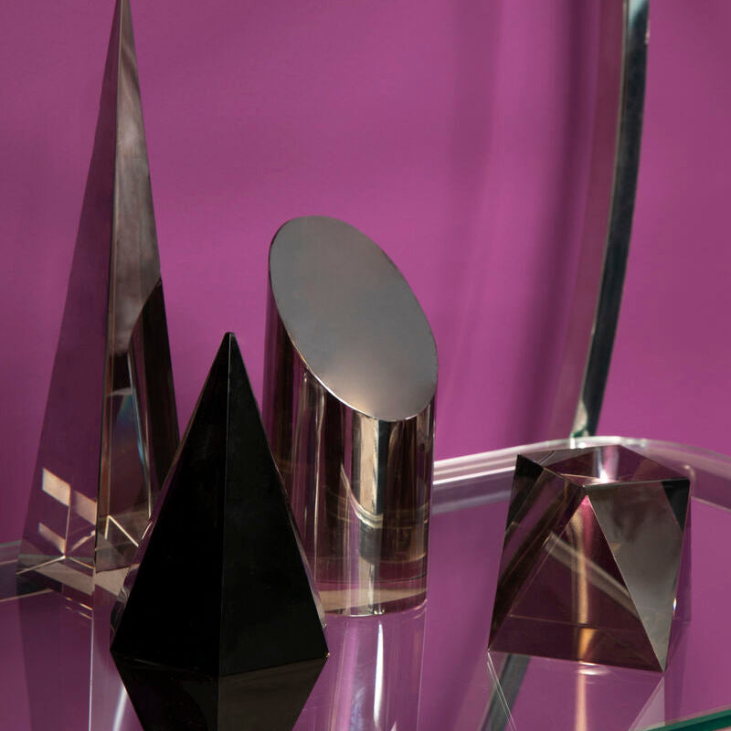 Set of geometric crystal sculptures on a reflective surface with a purple background