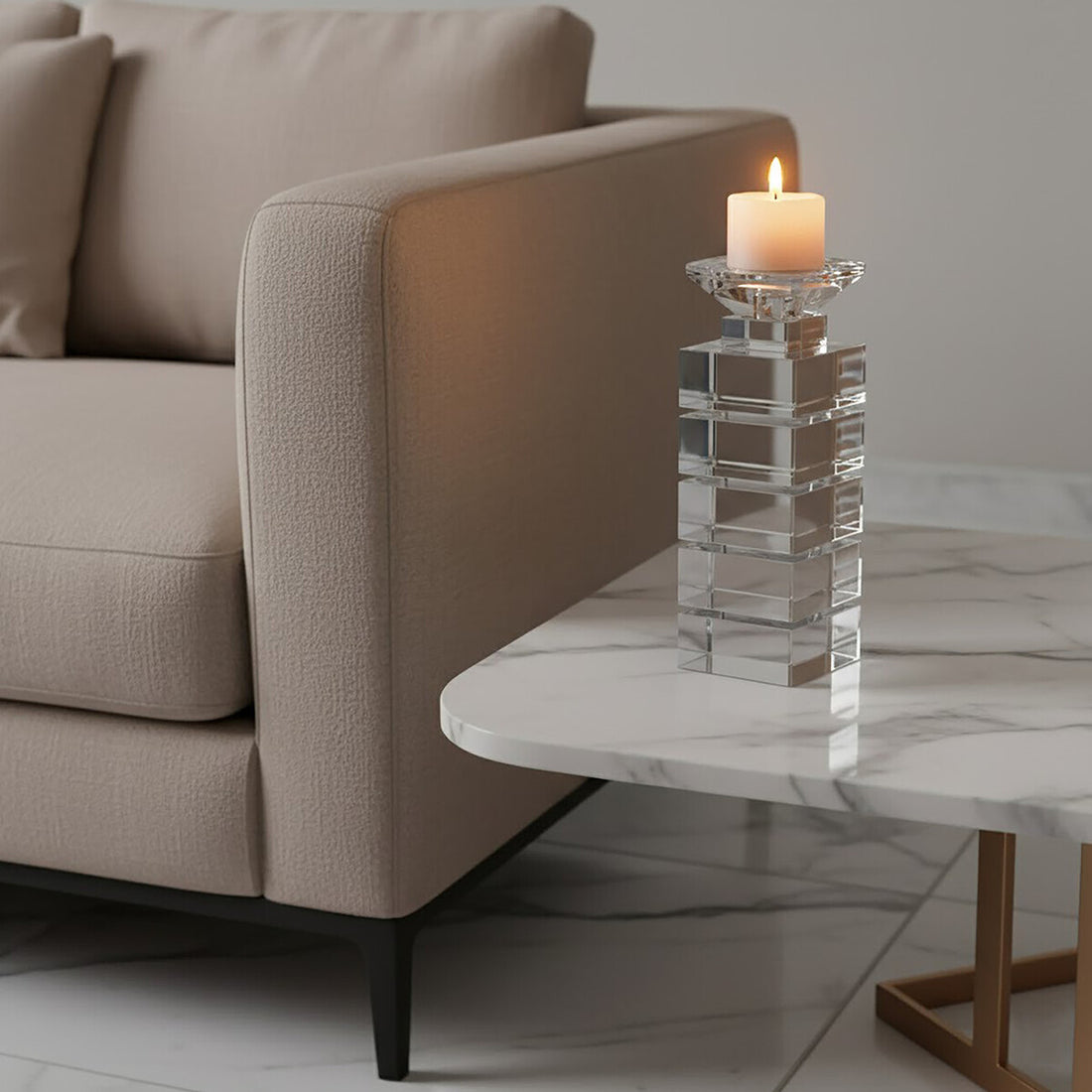 Candle in a crystal holder on a marble table next to a beige sofa