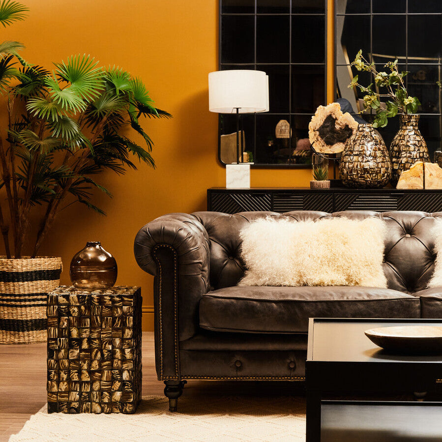 Living room with a brown leather sofa, decorative pillows, a coffee table, and a yellow wall.