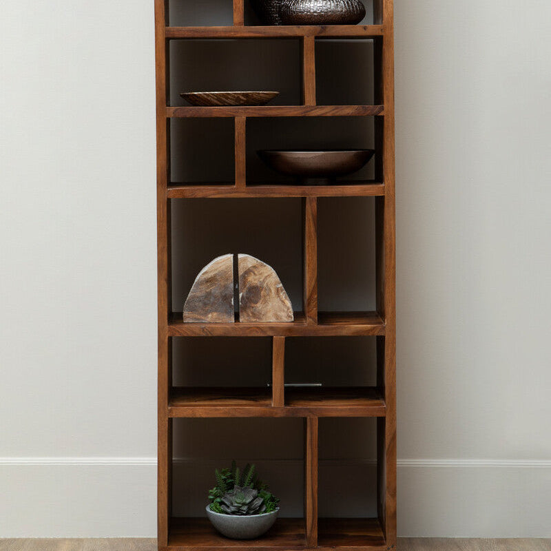 Tall wooden bookshelf with various decorative items against a white wall.