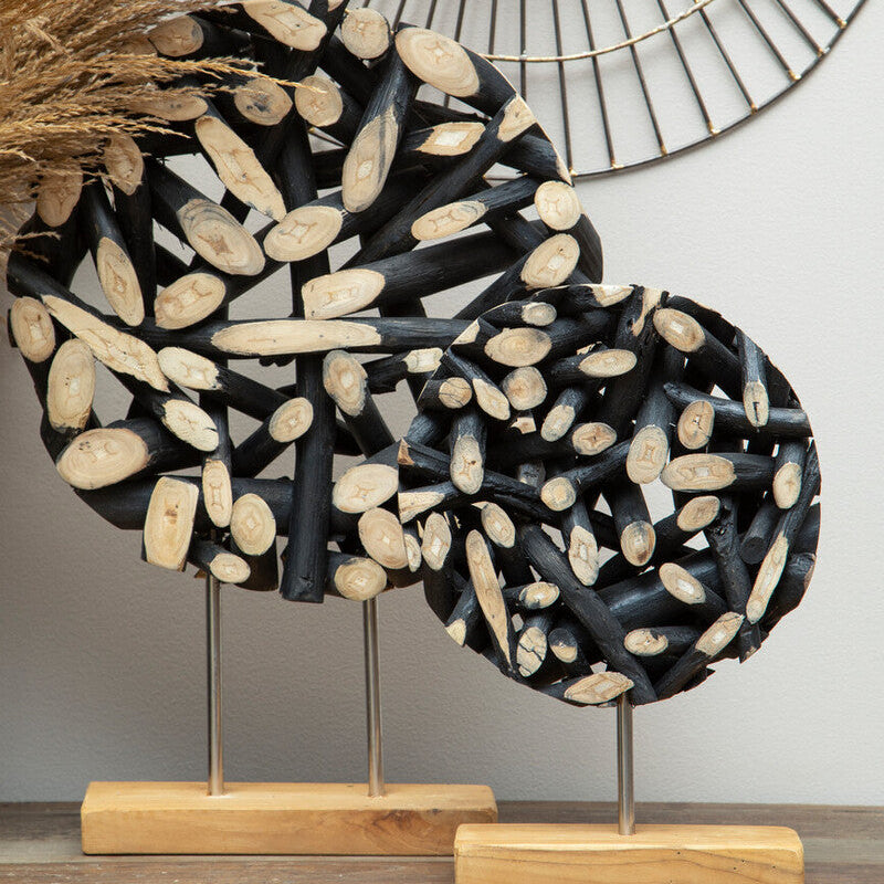 Decorative sculpture with black and beige stones on a wooden stand against a neutral wall.