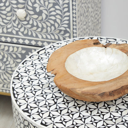 Decorative table with a geometric pattern and a wooden bowl on top.