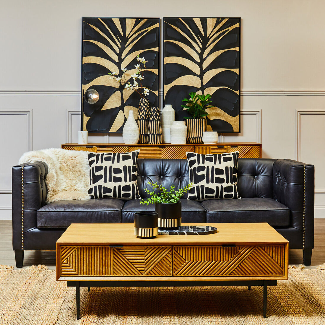Living room with black leather sofa, wooden coffee table, and decorative wall art.