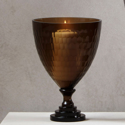 Brown glass goblet on a white surface with a neutral background