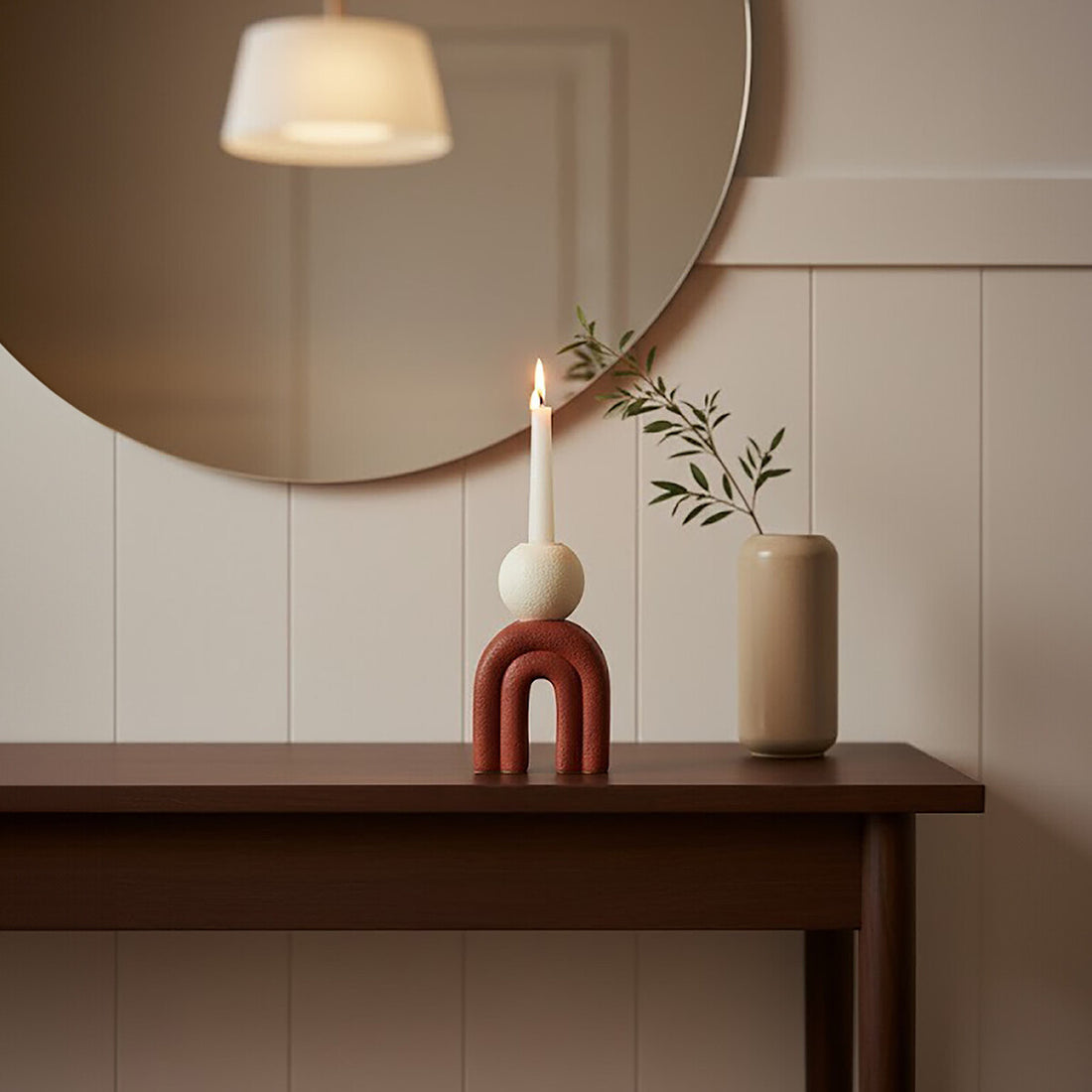 Decorative items on a wooden table with a round mirror above, against a beige wall.