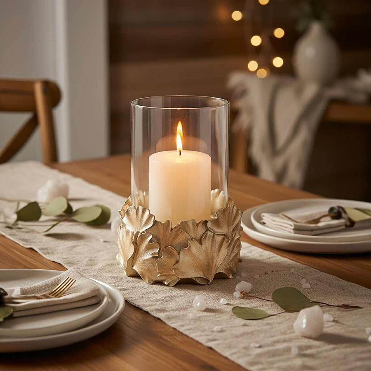 Candle in a decorative holder on a table setting with plates and cutlery.