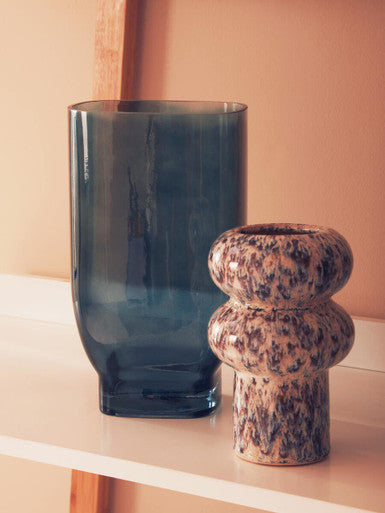 Blue glass vase and terracotta pot on a light surface with a beige background