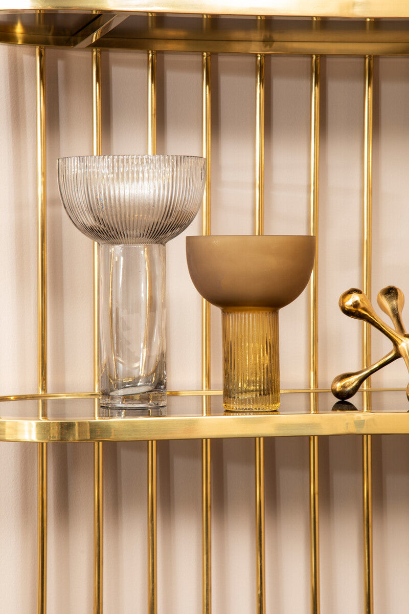 Decorative glass bowls on a gold shelf with a gold decorative object.