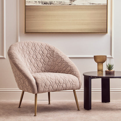 Beige armchair in a room with abstract art on the wall and a small table with a plant.