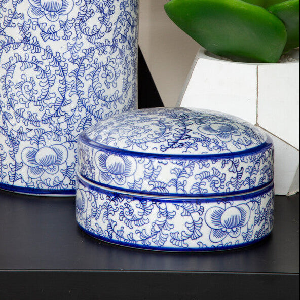 Blue and white patterned ceramic jars on a black shelf with a plant in the background.