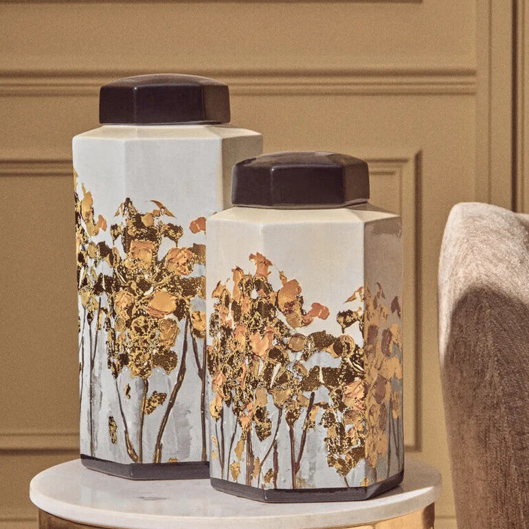 Decorative vases with floral patterns on a marble table against a beige wall.