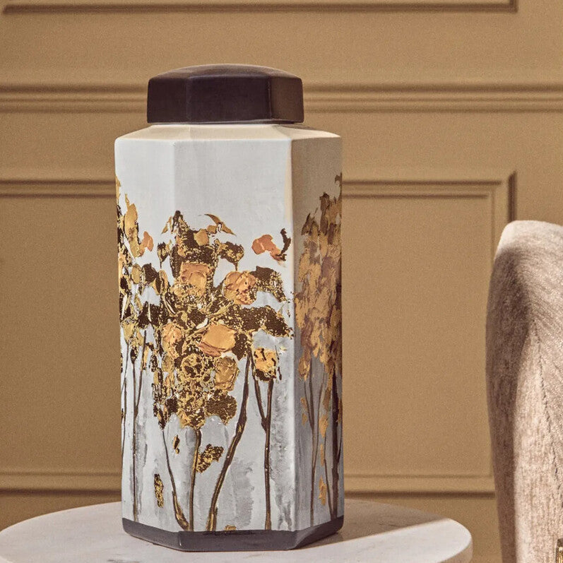 Decorative vase with floral patterns on a marble surface against a beige wall.