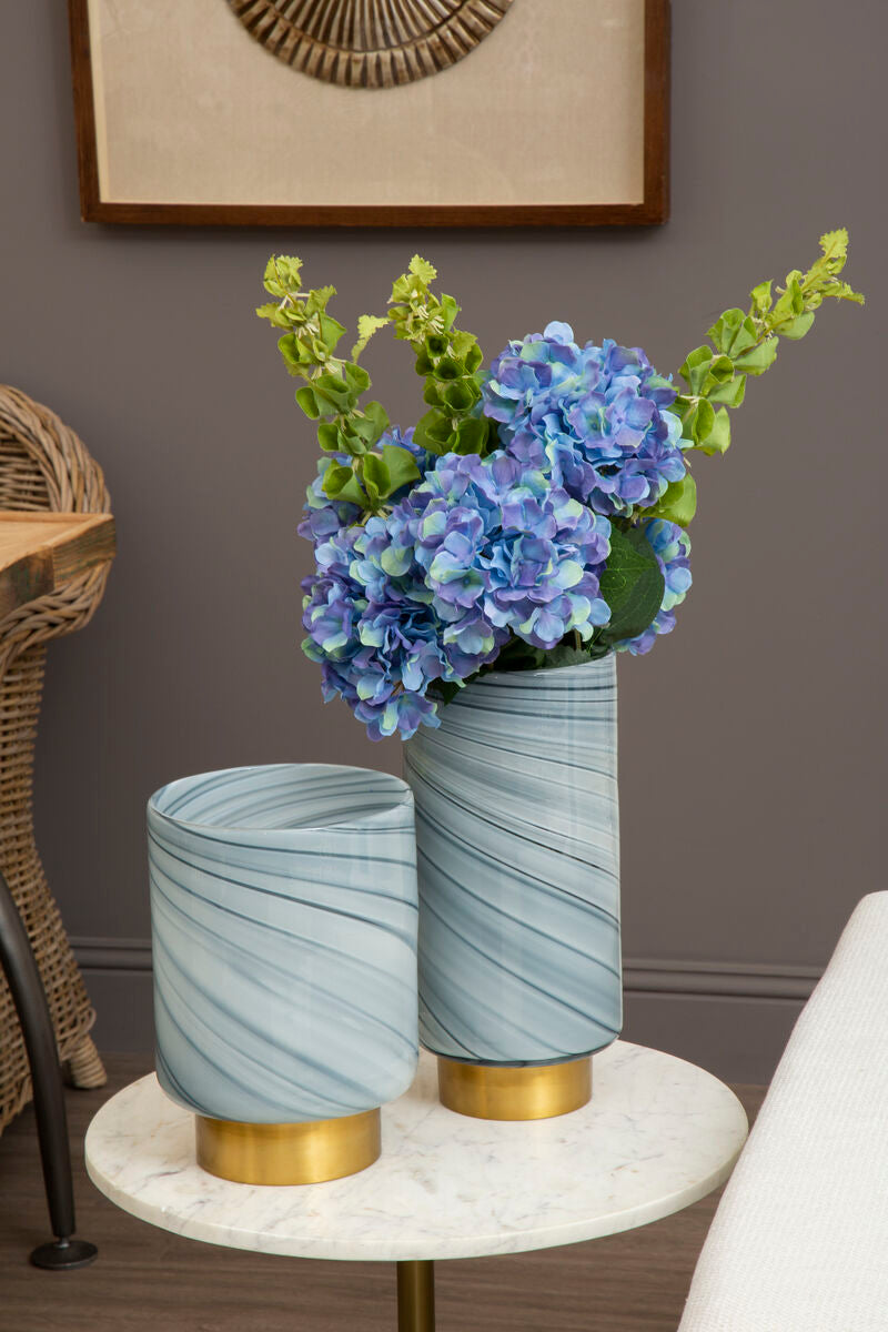 Two decorative vases with marbled design and gold bases on a marble table against a gray wall.