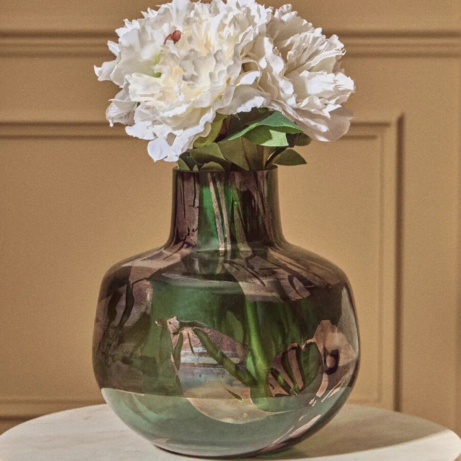 Glass vase with white flowers on a marble surface against a beige wall