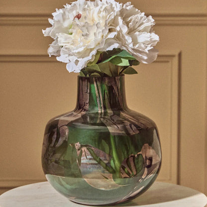 Glass vase with white flowers on a marble surface against a beige wall