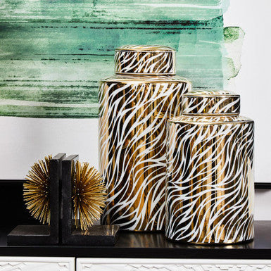 Decorative vases with zebra pattern on a shelf in front of a textured wall.