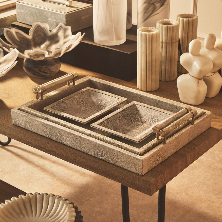Decorative items on a wooden table including a tray, candles, and sculptures.