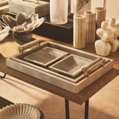 Decorative items on a wooden table including a tray, candles, and sculptures.