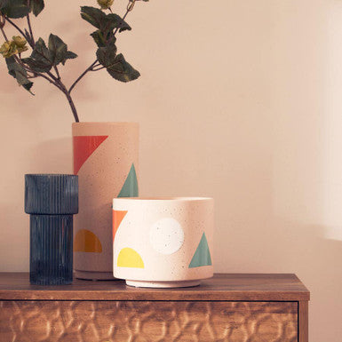 Three ceramic pots with geometric designs on a wooden surface.