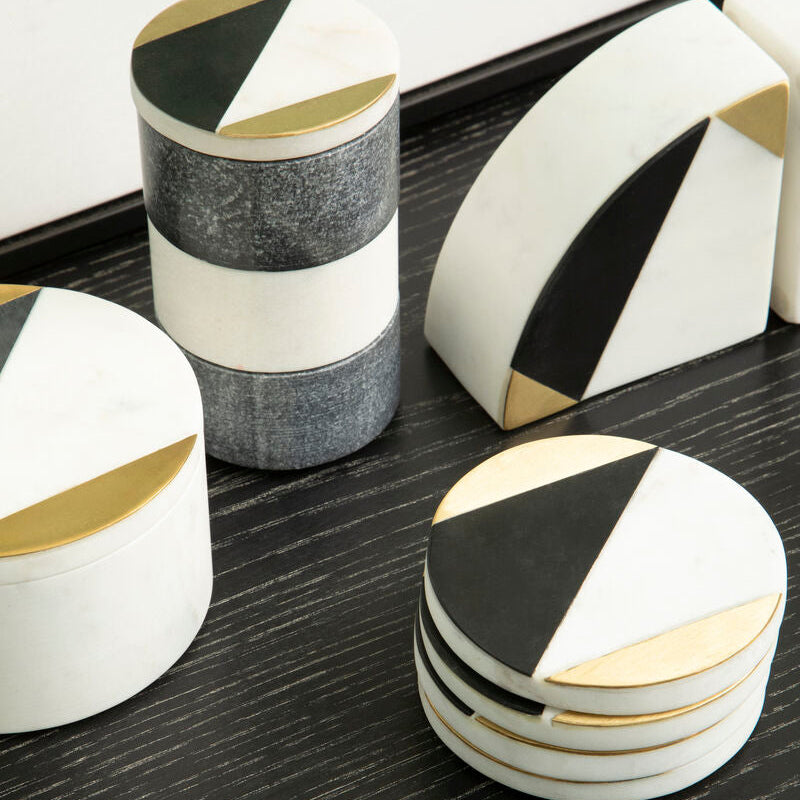 Set of geometric coasters with black, white, and gold design on a dark surface.