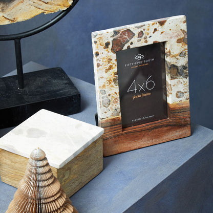 Decorative photo frame with natural stone and wood design on a shelf.